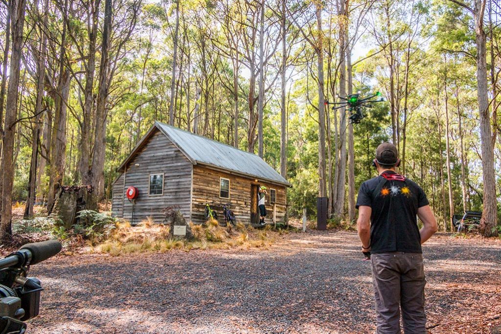Videographer with a drone filming Troy Brosnan in front of the Blue Derby budget accommodation