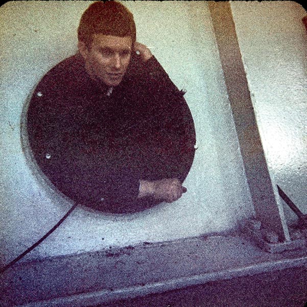 Graham ages 18 emerging from inside a large hydro turbine inspection bay.