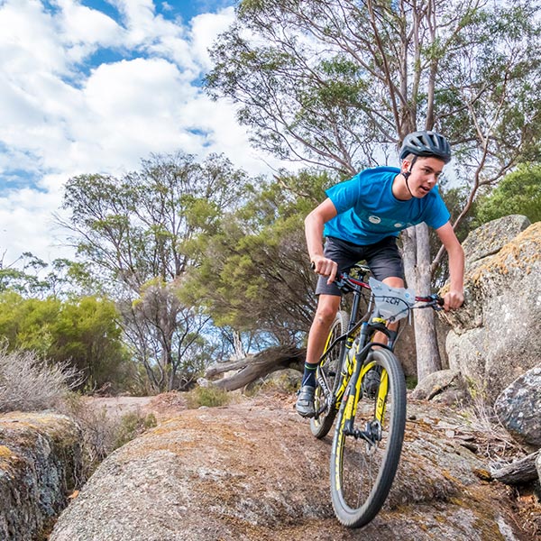 A young man on his mountain bike riding down a steep rock face on a Blue Derby mountain bike trail.