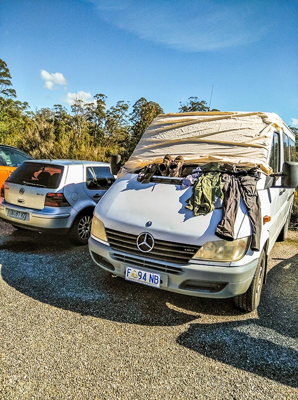 Our campervan with James's wet clothes and boots hanging from the windscreen in the Frenchmans Cap car park.