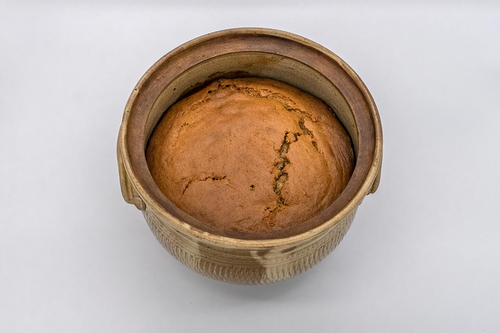 hand-made ceramic cooking pot containing freshly-baked golden-coloured apple pudding