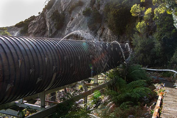 Water spouts rise above the wood stave pipeline where leaks have developed.