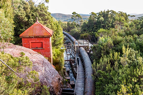 A red-painted former maintenance shed is next to the reconditioned wooden stave pipeline at Lake Margaret.