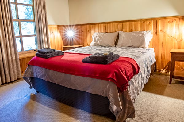 Queen-size bed in the wheelchair accessible second bedroom of Ah Moy cottage in Tasmania.