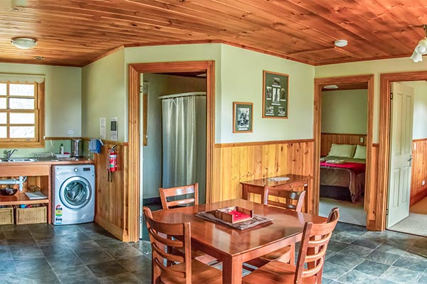 Interior of Ah Moy cottage showing kitchen and living area with doorways to the bathroom and two bedrooms.
