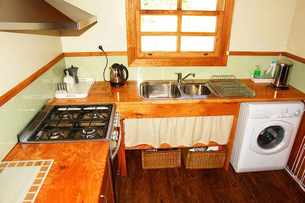 Kitchen in Ah Moy cottage showing the gas-top stove, electric oven, sink and washing machine.