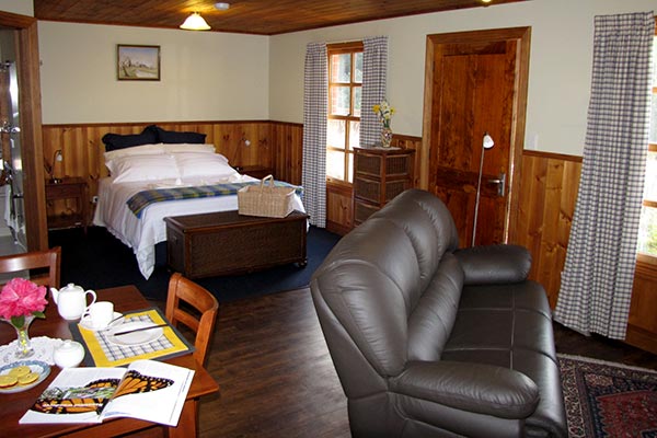 Interior of Fon Hock cottage showing the dining table, lounge sofa and queen bed.