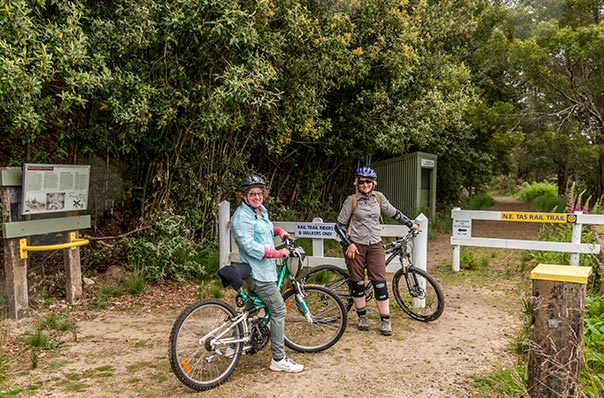 Two women with bicycles entering the North East rail trail