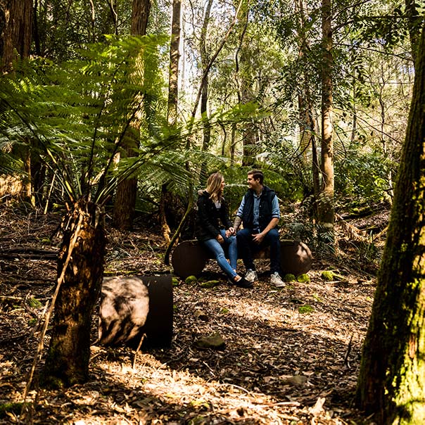 A young couple sit on a sandstone bench in the centre of the heritage Ah Ping mine.