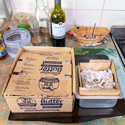 Cardboard has been placed over the cardboard box and aluminium foil has been placed over the fifth cake tin.