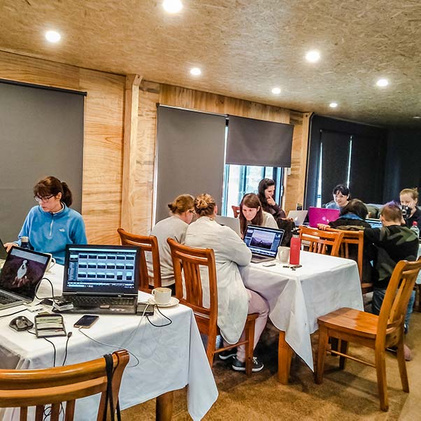 Inside the Barn participants are sitting at tables working on their lap-top computers.