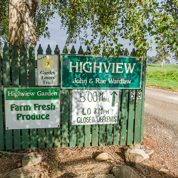 Green farm fence with signs advertising Highview fresh farm produce.