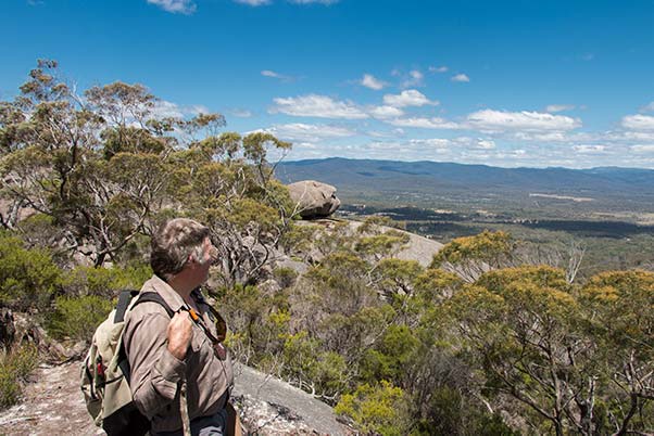 Graham is in the foreground looking out to a rock formation on the edge of an escarpment.
