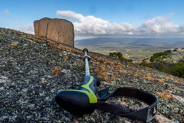 On a large slab of granite is a prone walking stick and in the background is the cube rock.