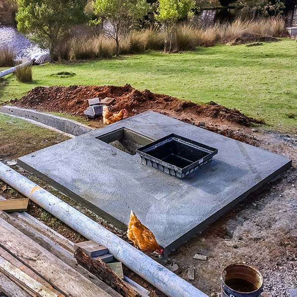 A cement slab has a well for installation of a micro-hydro generator and an outlet for the tail race.