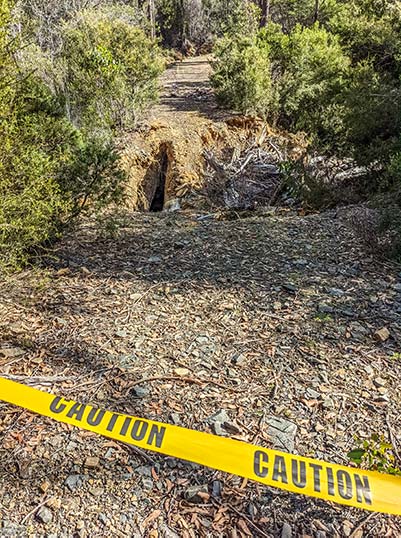 Yellow tape with the word: caution indicates that the bridge on the Meadstone Falls Road has collapsed.