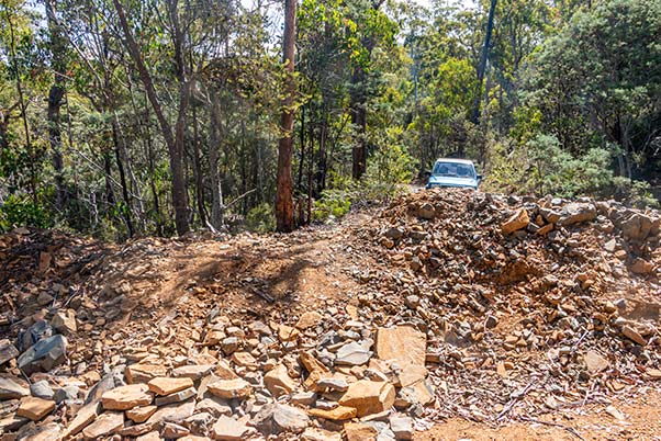 Our blue Feroza 4WD is sitting above a large excavation in the gravel road.