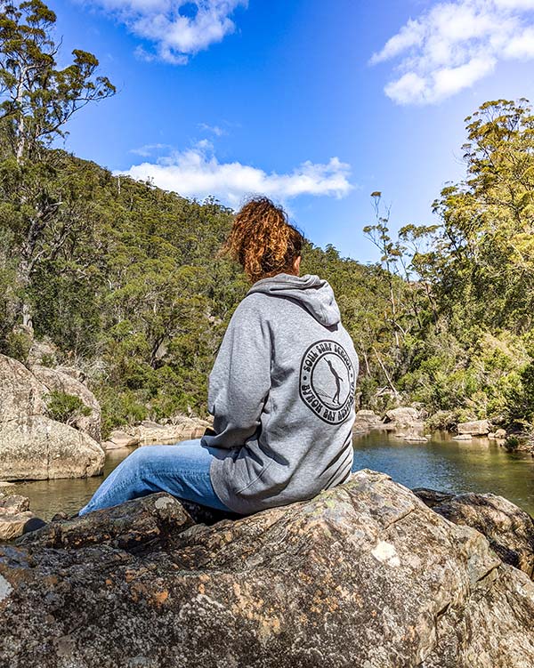 Swantje looking out over the water. Her back is turned towards the water and away from the camera.