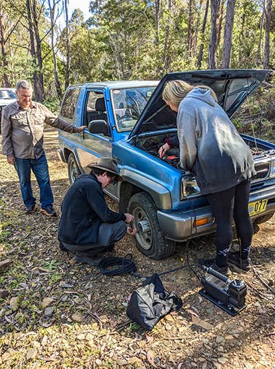 James is changing the front right tire on the Feroza. Graham and Zarsha are assisting.