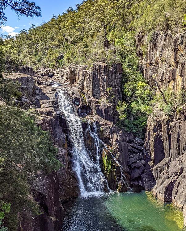 Meadstone Falls plummets down over dark dolerite rock into a deep clear rock pool. 