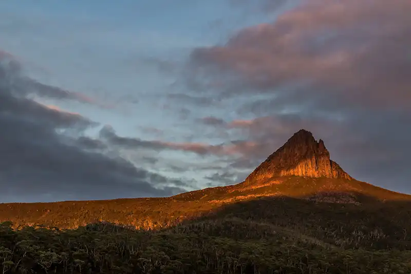 Barn Bluff is a golden colour against a link sky just after sunrise.