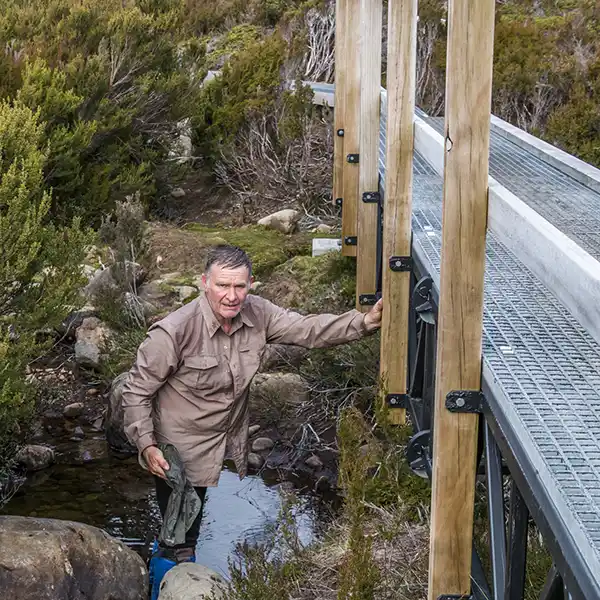 Graham is refilling our water bottles in a shallow creek near a bridge on day 4 of the Overland track walk.