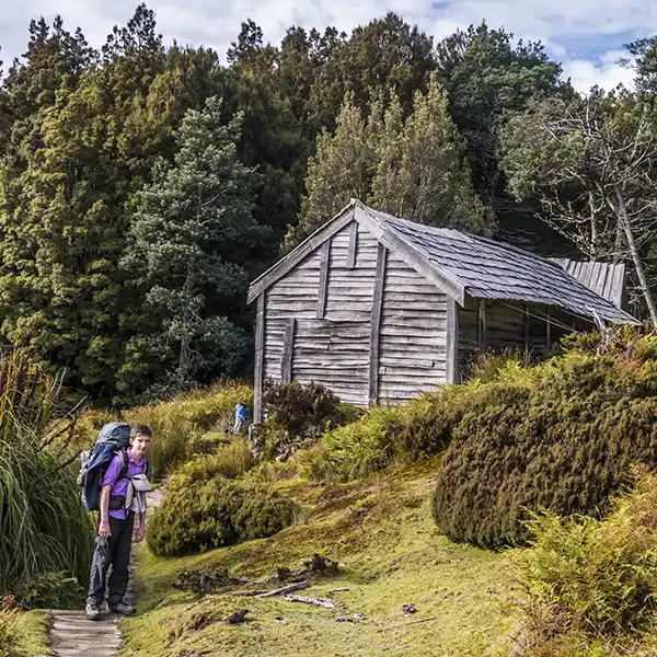 James is wearing his back pack and standing in front of the historic Du Cane hut.