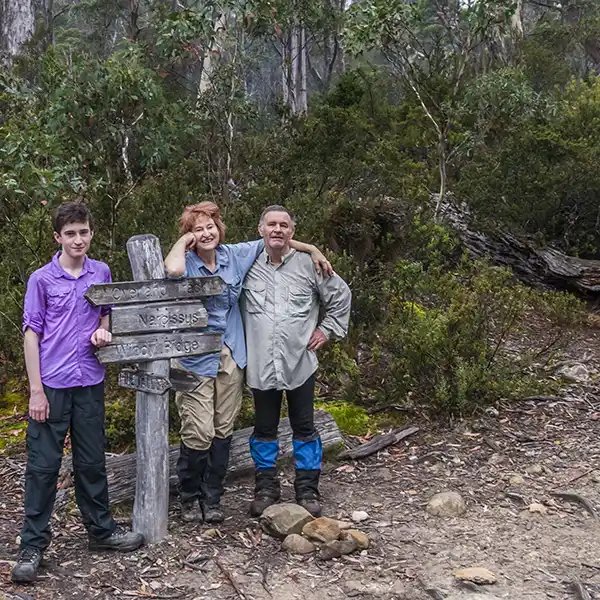 James, Christin and Graham are leaning on a sign post at the junction with the Pine Valley track.