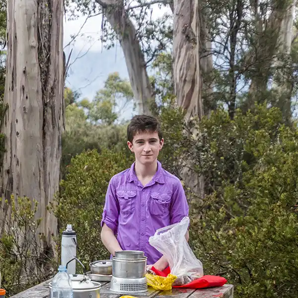 James is standing at a picnic table with hot water brewing for a cup of tea.