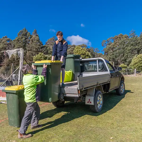 Graham and James lifting rubbish bins onto the back of a truck at Tin Dragon Cottages, Tasmania