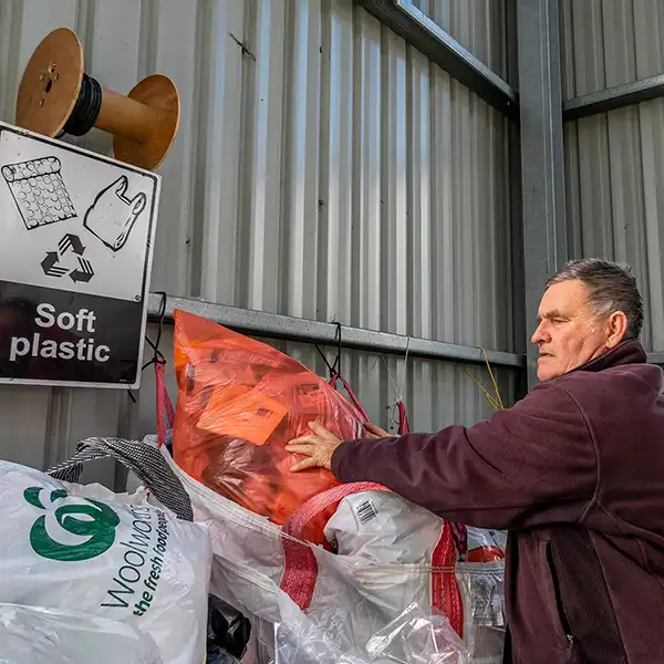 Graham placing a large bag of soft plastics into a bin at the recycling plant
