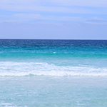 Clear aqua ocean water meets a blue sky.