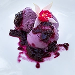 Three scoups of blueberry gelato on a white plate