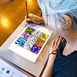 A lady drawing with a coloured pencil