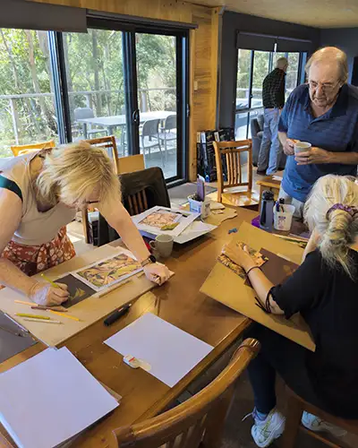 Two srt retreat students are focused on their work while Richard is assisting one student.