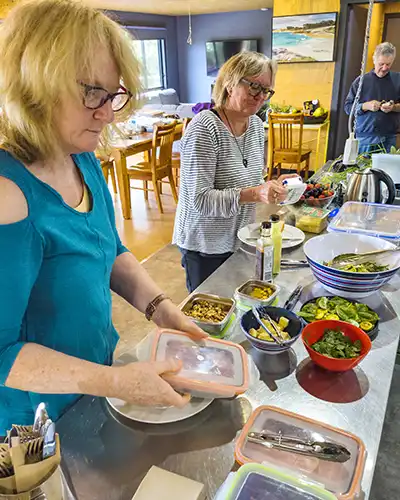 Two art students are selecting their lunches from a variety of fresh salads, cheeses and meats.
