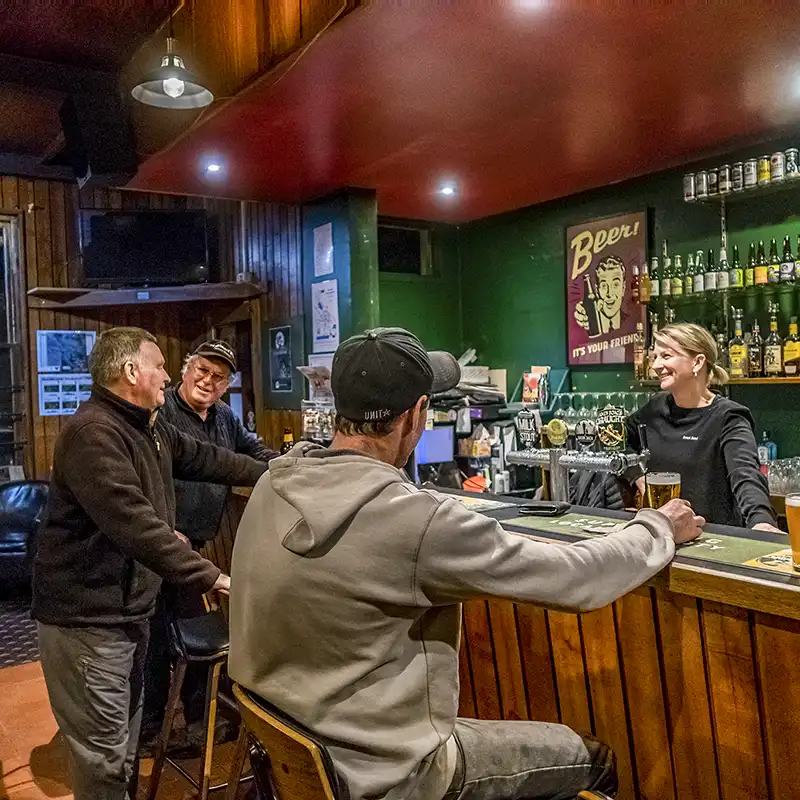 Three men sitting at an hotel bar being served by a woman