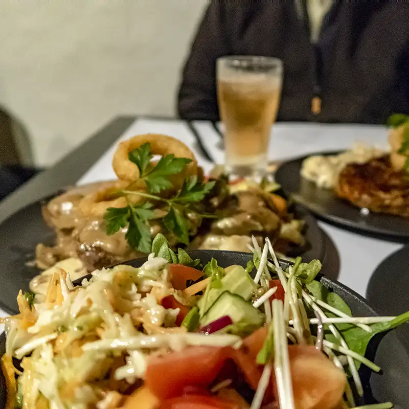 Pub meals on black plates and a glass of beer as an example of where to eat near Tin Dragon Cottages.