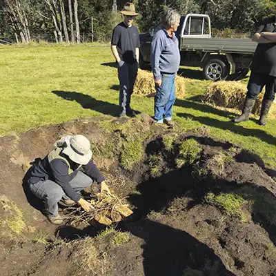 Christina starts the fire in the bottom of the pit to make the biochar.