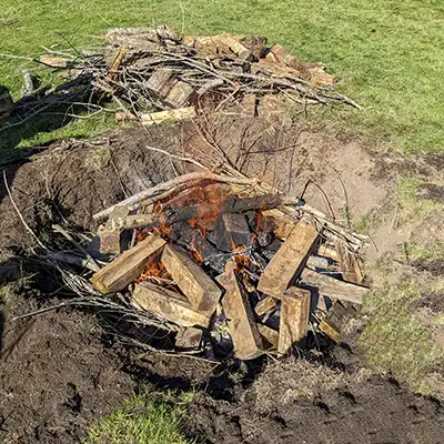 The fire pit is about half-filled with timber fuel and the fire is beginning to make biochar.