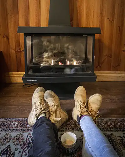 Romantic couples getaway cottage in Tasmania. A man and woman are drinking hot chocolate in front of the fireplace in Chintock studio spa cottages.