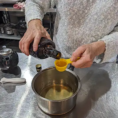 A woman is pouring a small quantity of brandy into a measuring cup.