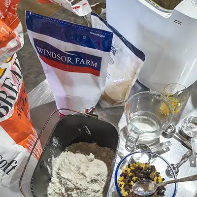 Ingredients for makeing hot cross buns: spices, dried fruits, bread-making flour and egg are shown.