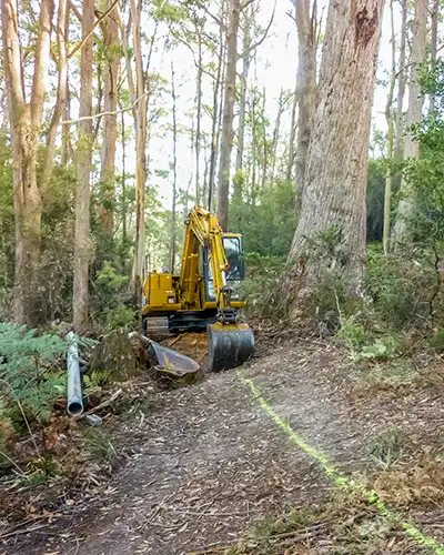 An excavator starts digging the trench for our micro hydro water pipe.