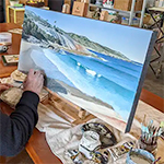 A man is painting an ocean scene