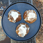 Three spicy ginger biscuits on a dark coloured plate.