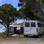 A white sprinter van parked next to a beach on Flinders Island