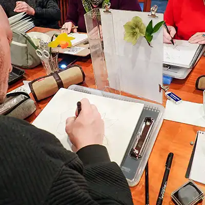A man is drawing a flower, which is arranged in front of him.