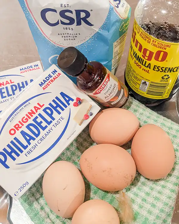 The ingredients for the baked cheesecake include sugar, cream cheese, eggs, vanilla and almond essence.