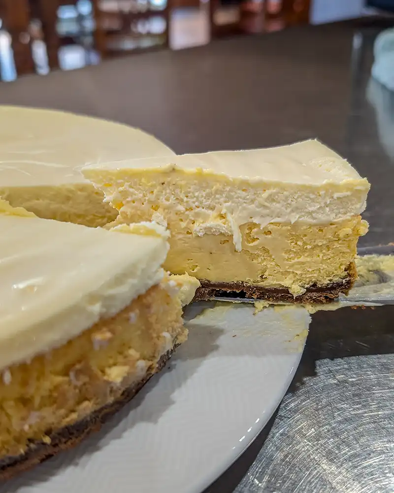 Baked cheesecake with one slice being removed to show the creamy testure.